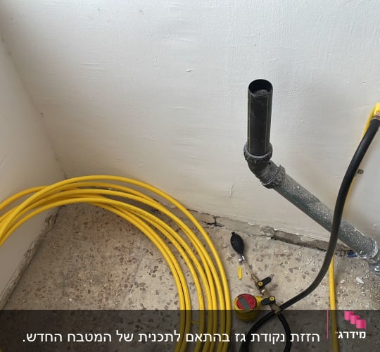 צינור גז צהוב מגולגל ליד קיר עם חיבורים